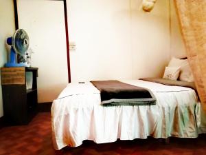 1 dormitorio con 1 cama blanca y ventilador en แม่อุ๊ยโฮมสเตย์&mae uai homestay, en Ban Pok Nai
