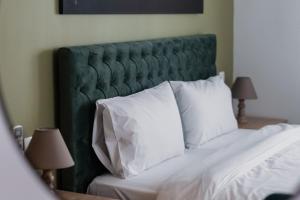 a bed with a green headboard and white pillows at Ethra Suite 2 in Volos