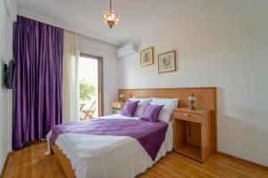 a bedroom with a bed with purple sheets and a window at GRAPE DATÇA in Kızlanköy