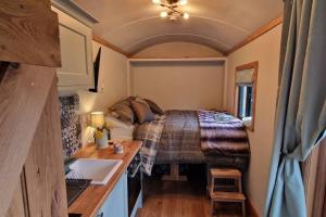 um quarto com uma cama numa pequena casa em Cosy Owl - Shepherds Hut em Longford