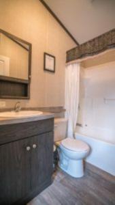 une salle de bain avec toilettes, lavabo et miroir dans l'établissement 2 Bedroom Cottage Tamarack Trail 1, à Campbellford