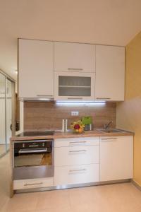 a kitchen with white cabinets and a stainless steel oven at Cozy studio with a terrace near Slavija square in Sajmište