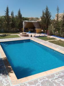 une piscine bleue avec une maison en arrière-plan dans l'établissement Essaouira à louer, appartement avec piscine privée, à Bou Mkila