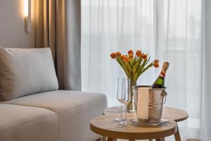 Termy Karkonosze Resort & Spa في Staniszów: غرفة معيشة مع طاولة مع زجاجة من الشمبانيا والورود