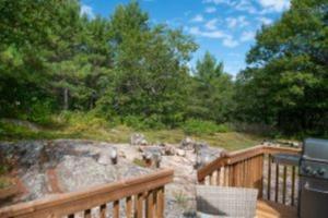 a wooden deck with a fence and a stone wall at 2 Bedroom Cottage Maple Ridge 9 in Gravenhurst
