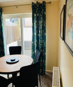 ein Esszimmer mit einem Tisch, Stühlen und einem Fenster in der Unterkunft Westwood Drive in Treharris