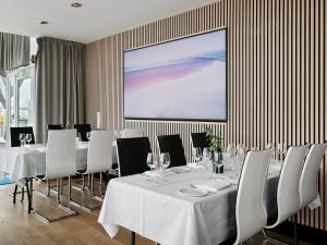 une salle de conférence avec des tables et des chaises blanches et un écran de projection dans l'établissement Quality Hotel Maritim, à Haugesund