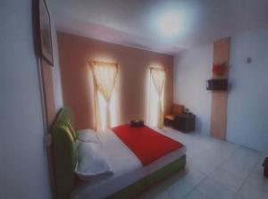 a bedroom with a bed with a red blanket and two windows at BOTANIA HOMESTAY BATAM in Nongsa