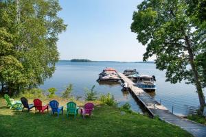 a group of chairs sitting on the grass next to a dock at Newly Renovated 2 Bedroom Beach Front Condo 3C in Lanark