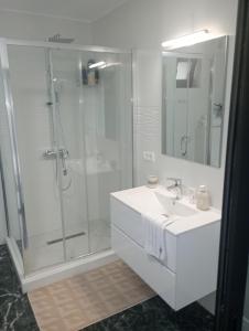 a white bathroom with a shower and a sink at Izabella Guest House in Săcele