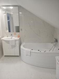 a white bathroom with a tub and a sink at Izabella Guest House in Săcele
