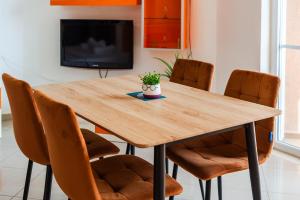 un tavolo di legno con sedie e una tv di Orange Beachfront Studio by PS a Golem