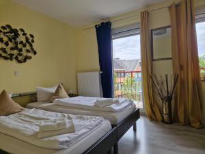 2 Betten in einem Zimmer mit einem großen Fenster in der Unterkunft Ricks City Hotel in Trier