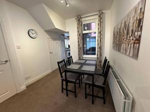 a dining room with a table and chairs and a clock at 2br Stylish Ormeau Road House in Belfast