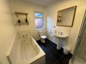 a bathroom with a tub and a toilet and a sink at 2br Stylish Ormeau Road House in Belfast