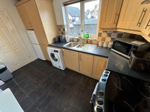 a kitchen with a sink and a microwave at 2br Stylish Ormeau Road House in Belfast