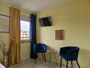 um quarto com duas cadeiras e uma televisão na parede em Ricks City Hotel em Trier