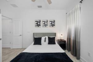 a white bedroom with a large bed with black pillows at Luxury Modern Villa w Pool Jacuzzi Amenities in Tampa