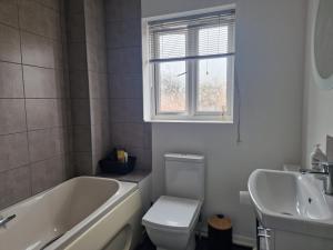 a bathroom with a tub and a toilet and a sink at FamilyFriendly- Sleep5- FreeParking- PrivateGarden in Rochester