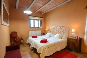 Un dormitorio con una cama blanca con toallas rojas. en Can Guinau en Aiguaviva