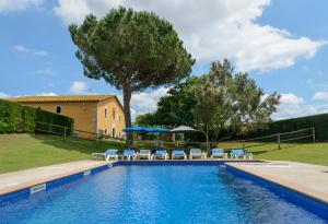 una piscina con sedie e ombrelloni accanto a una casa di Can Guinau ad Aiguaviva