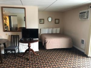 a hotel room with a bed and a desk with a computer at Colonial Inn Ellsworth in Ellsworth