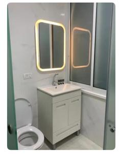 a bathroom with a toilet and a sink and two windows at Romy boutique in Netanya