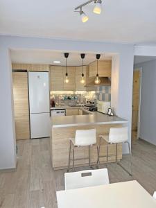 a kitchen with a counter and white chairs in it at Estación Tren Reformado 2 habitaciones in Alicante