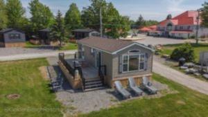 a small house with a porch and some chairs at 2 Bedroom Harbor Front Cottage 2 in Roseneath