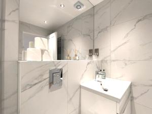 Baño blanco con lavabo y espejo en Edinburgh Aparthotel, en Edimburgo