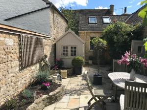a patio with a table and chairs in front of a house at Fabulous Grade 2 Listed Home in Heart of Stow in Stow on the Wold