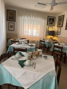 a dining room with tables with blue and white tablecloths at Albergo La Scogliera in Castiglione della Pescaia