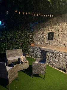 eine Terrasse mit Stühlen, einem Tisch und einer Steinmauer in der Unterkunft ViSTAMaRE Apartment in Opatija