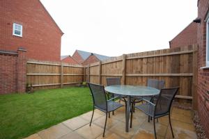 a patio with a table and chairs and a fence at DBS Serviced Apartments - The Mews in Castle Donington