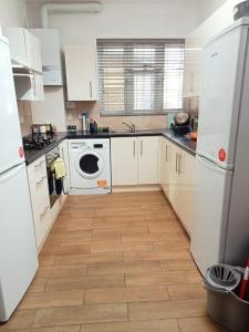a kitchen with white cabinets and a washer and dryer at RAHAL BARNET in Barnet