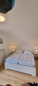 a white bed in a room with two tables at Hahnenkleer Tied 2 in Goslar