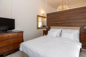 a bedroom with a white bed and a television at Apartments Villa Castello in Crikvenica