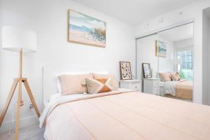 a white bedroom with a bed and a mirror at 1BD & Sofa Bed next to UofT! in Toronto