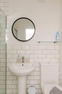 a white bathroom with a sink and a mirror at The Old Bank Beautiful Cotswold House with Huge Garden in Mickleton