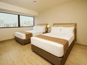 Habitación de hotel con 2 camas y ventana grande. en Estelar Apartamentos Bellavista, en Lima