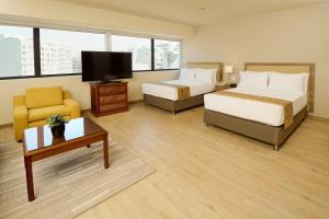 Habitación de hotel con 2 camas y TV de pantalla plana. en Estelar Apartamentos Bellavista en Lima