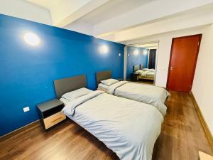 two beds in a room with a blue wall at Arshakunyats 88 TopHouse in Yerevan