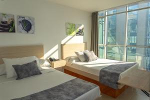 ein Hotelzimmer mit zwei Betten und einem Fenster in der Unterkunft Hotel Alcaravan Medellín in Medellín