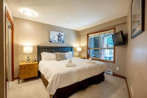 a bedroom with a large bed and a window at True Ski in Ski out Condo with hot tub and pool at the Aspens in Whistler