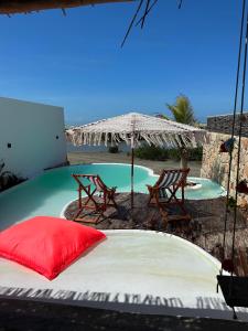 a bed and two chairs and an umbrella next to a pool at Villakite luxury in Itarema