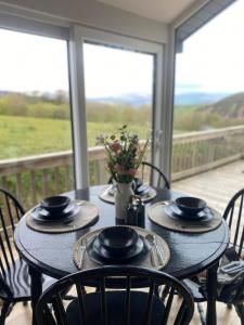 a table with four chairs on a porch at Glyndwr Way Cabin in Machynlleth
