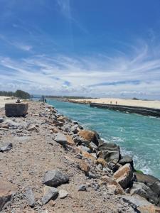 a rocky shore with a beach and the ocean at Chalés Lar Doce Mar Camacho SC in Jaguaruna +5 photos