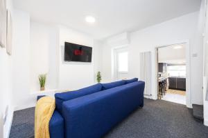 a blue couch in a living room with a table at 4 beds home, 3 baths, sleeps 8, free parking, contractors, trades in Purfleet