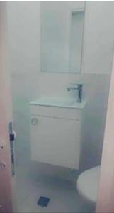 La salle de bains blanche est pourvue de toilettes et d'un lavabo. dans l'établissement Romy suites Deluxe, à Netanya