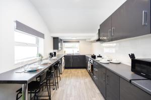a large kitchen with black cabinets and black counter tops at 4 beds home, 3 baths, sleeps 8, free parking, contractors, trades in Purfleet